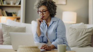 Femme qui réfléchit pendant qu'elle utilise son ordinateur portable